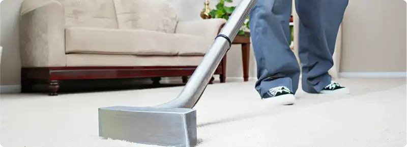 Carpet cleaning technician using a hot-water extraction wand on a light-colored carpet in a living room, Staten Island, NY.