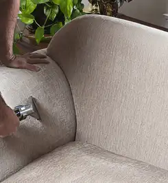 Professional upholstery cleaner deep-cleaning a fabric sofa with a handheld extraction tool and hose Staten Island, NY.